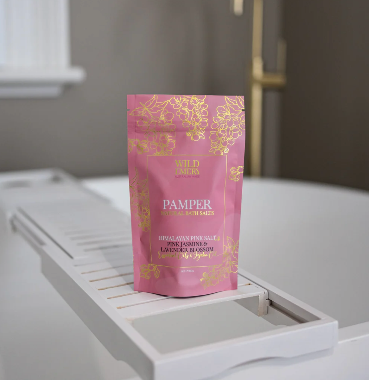 Pink package of Wild Earth Pamper bath salts on a white surface with a blurred background